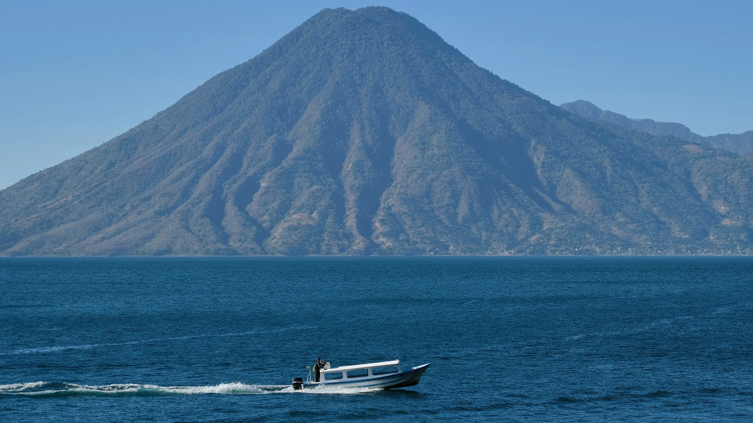 Motorboat on Lake Atitlán with a volcano in the background.