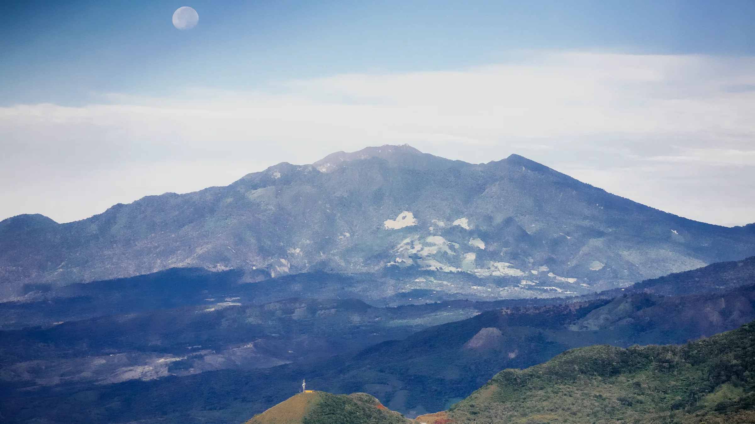 Slopes of Barú Volcano with scattered clouds and hills in the foreground.