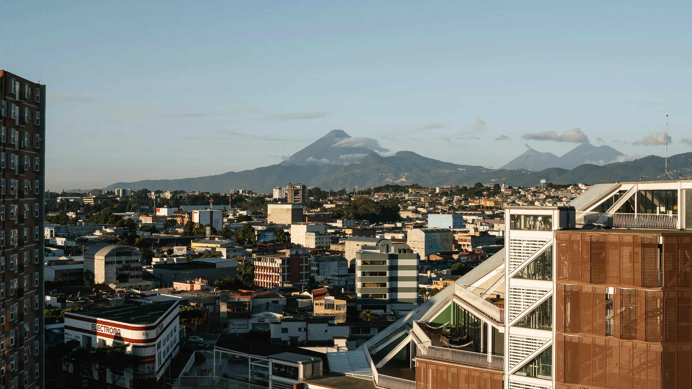 Buildings in Guatemala City with volcanoes on the horizon.