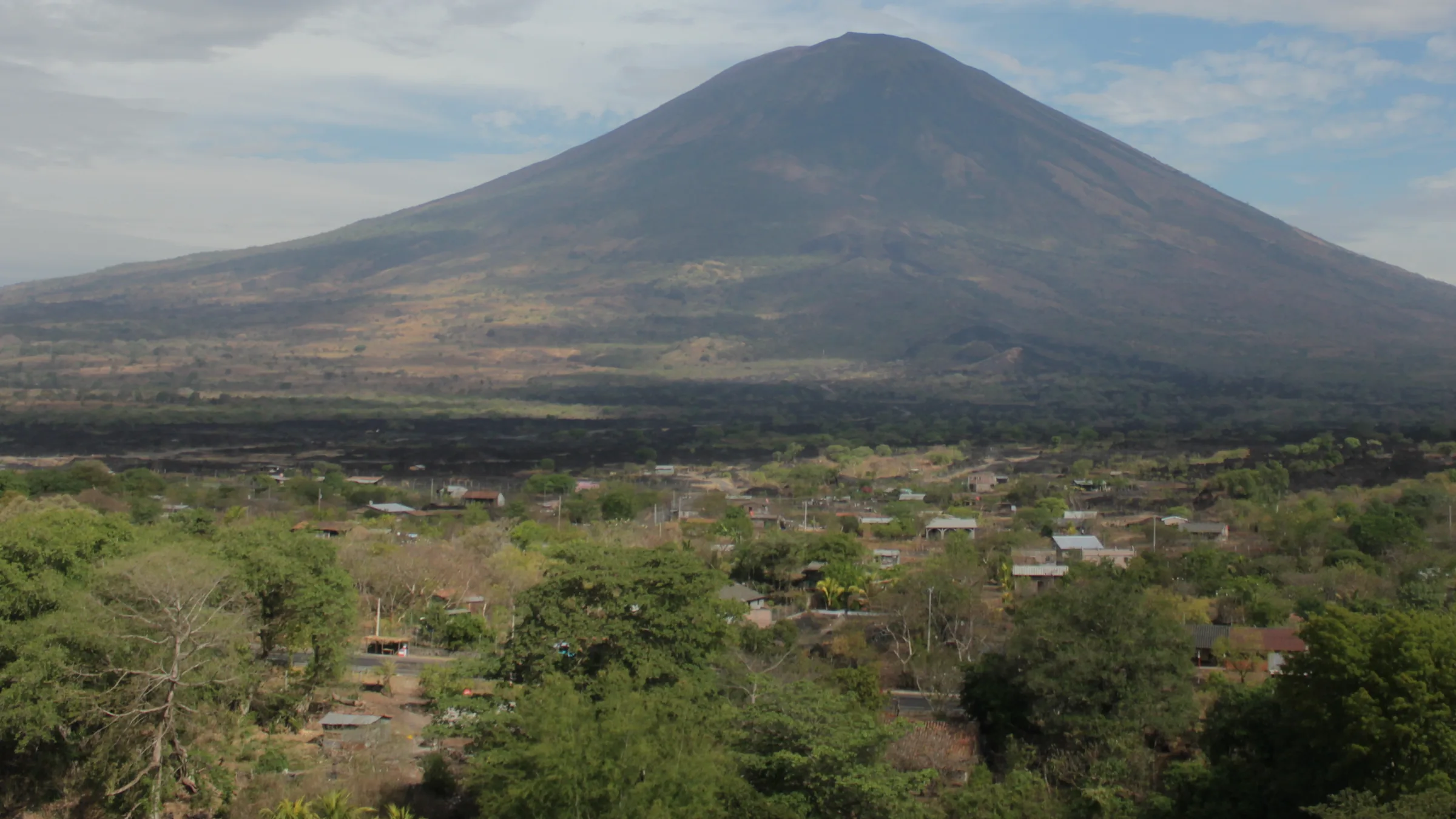 San Miguel volcano (Chaparrastique), with slopes, trees and scattered houses in the foreground.