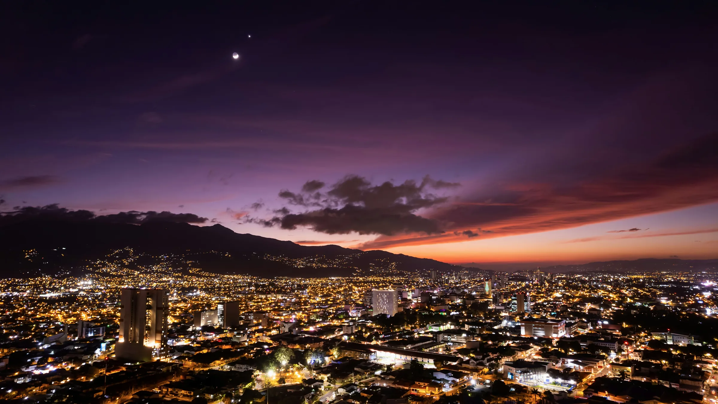 City lights in San José beneath a pink and purple sky.
