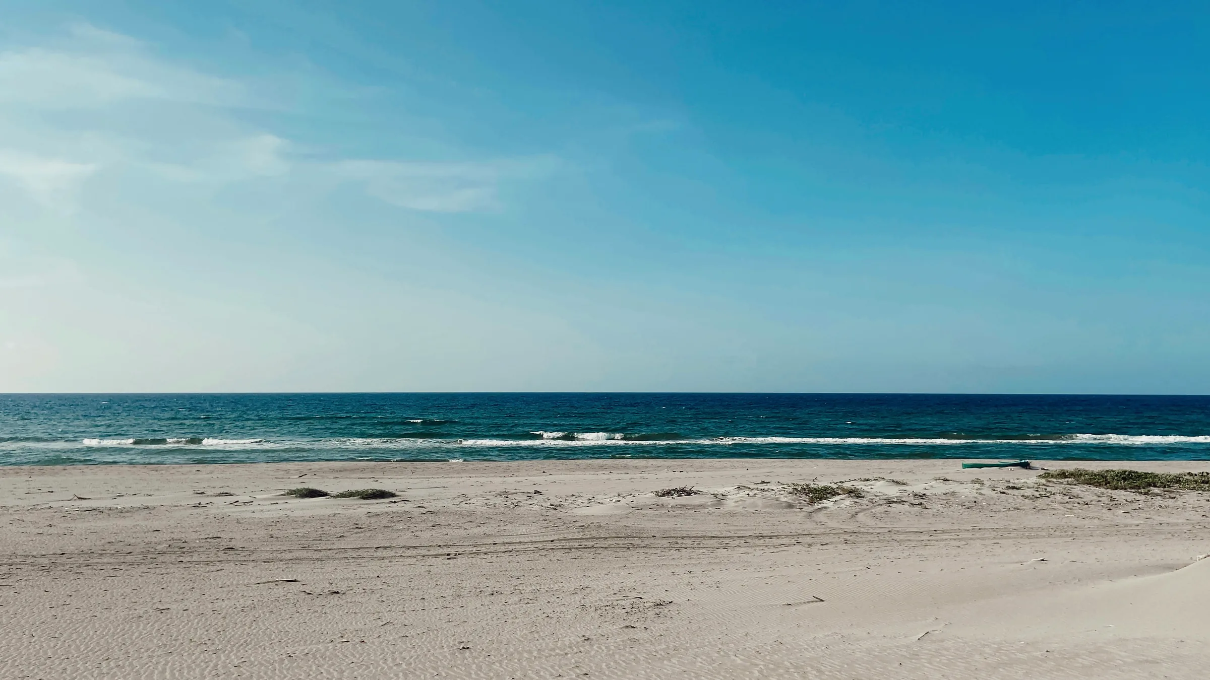 Sandy beach with low waves and blue sky in Tela.
