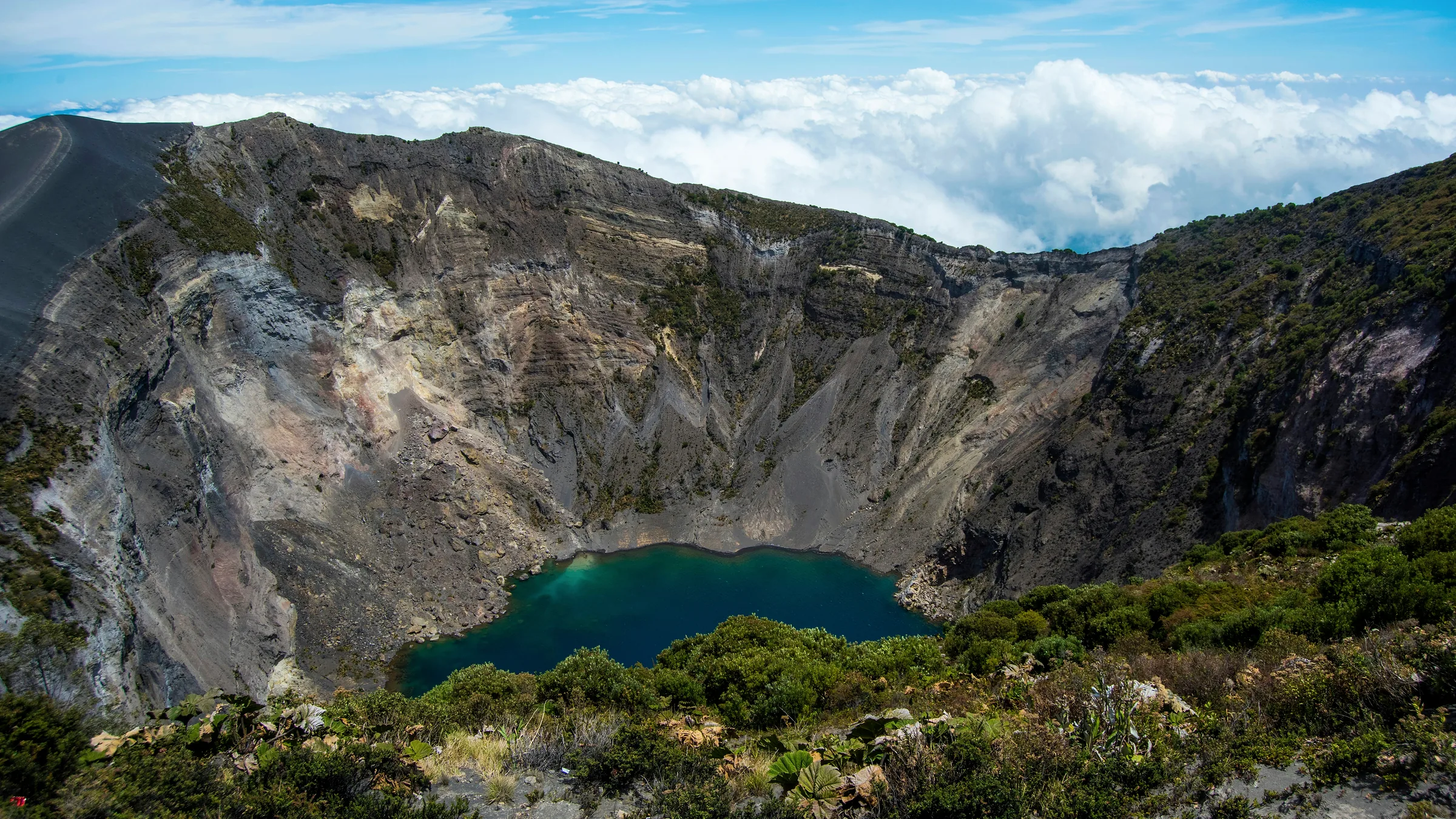 Lake at the bottom of a volcanic crater surrounded by rocky walls.