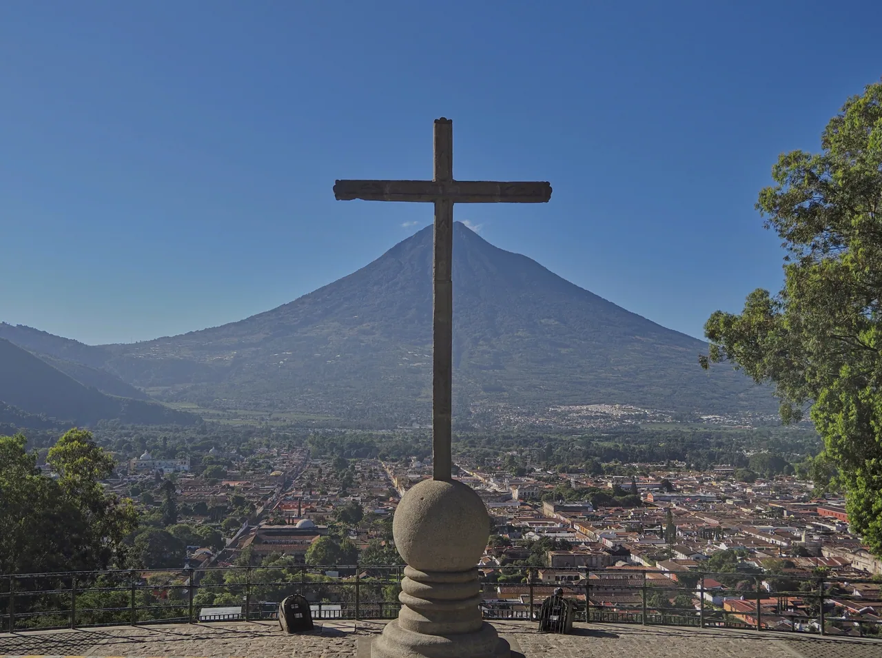 Stone cross with Antigua and Agua Volcano in the background.