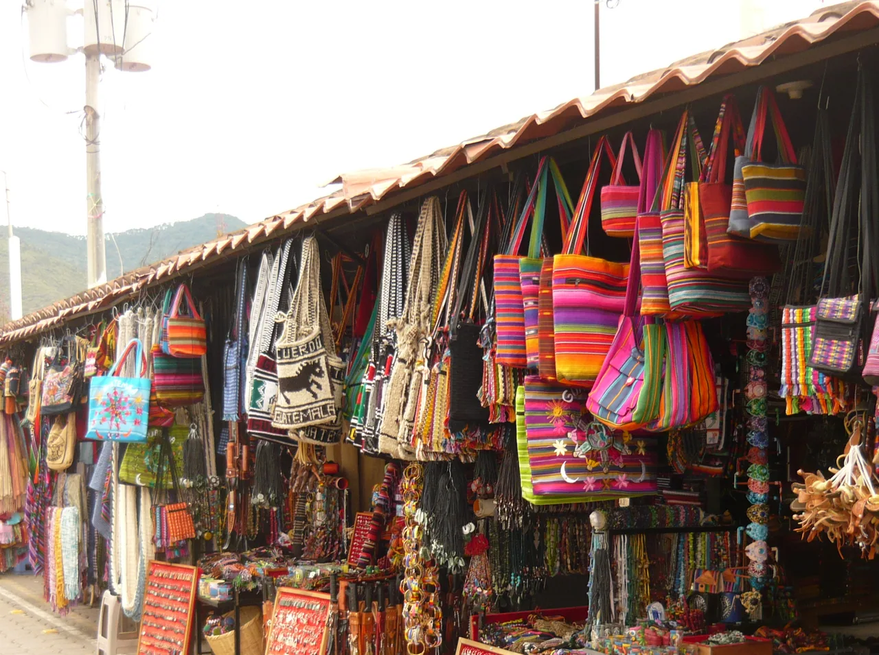 Aisle of stalls with bags and textiles at a market in Antigua.