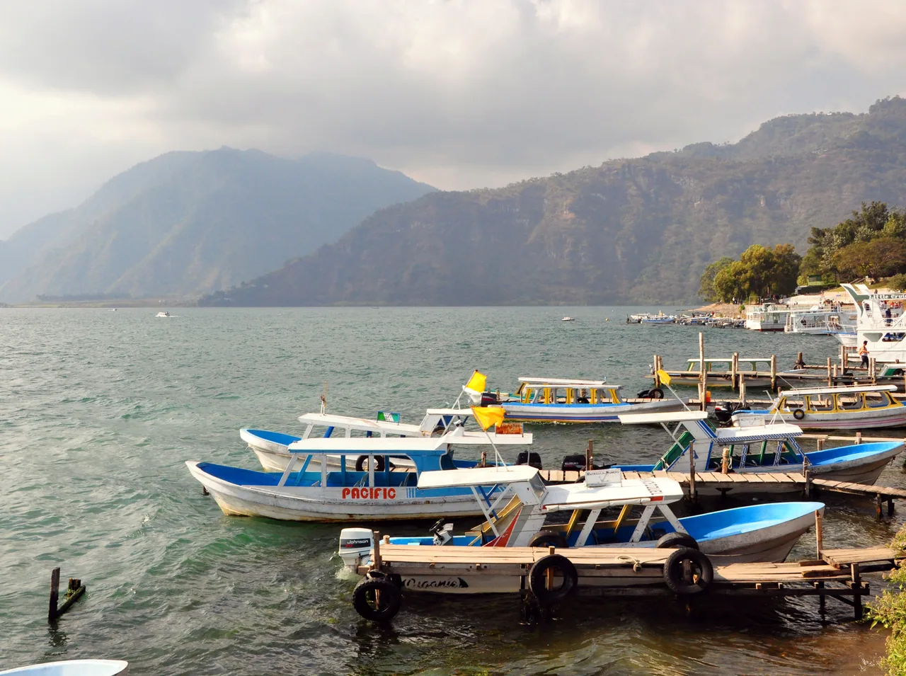 Boats beside a wooden dock in Panajachel, with the lake and mountains behind.