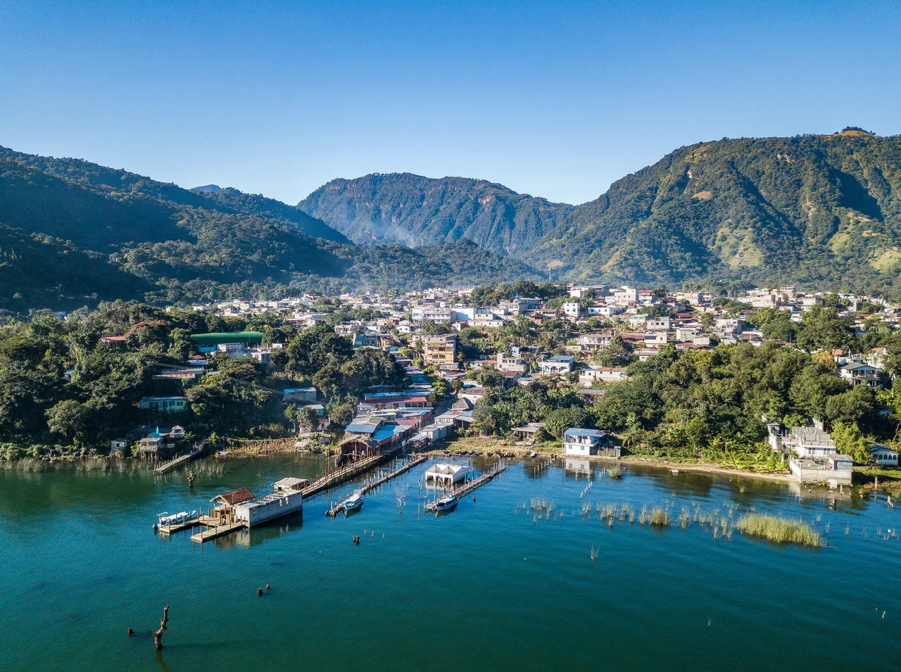 Aerial view of San Juan La Laguna beside the lake, with mountains behind.