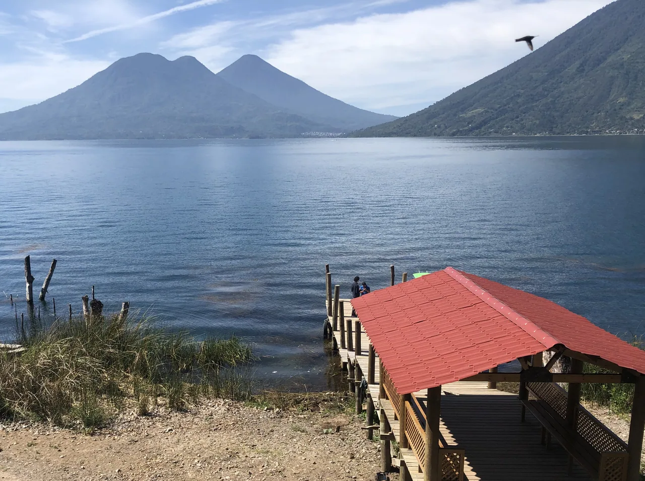 Red-roofed dock in San Marcos La Laguna, with the lake and volcanoes behind.
