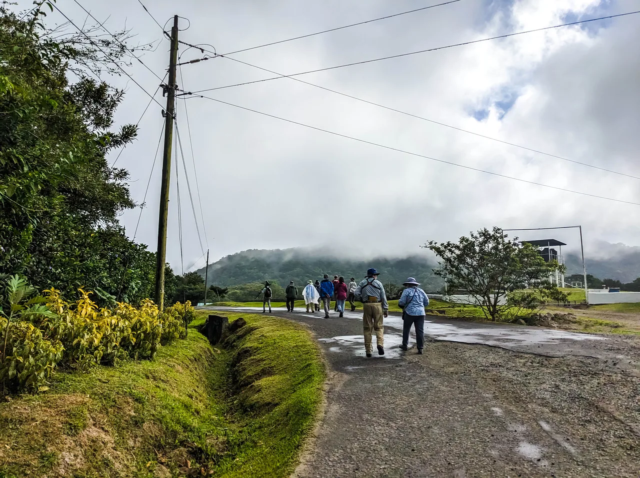Excursionistas de espaldas por un camino húmedo, con Cerro Gaital cubierto de nubes al fondo.