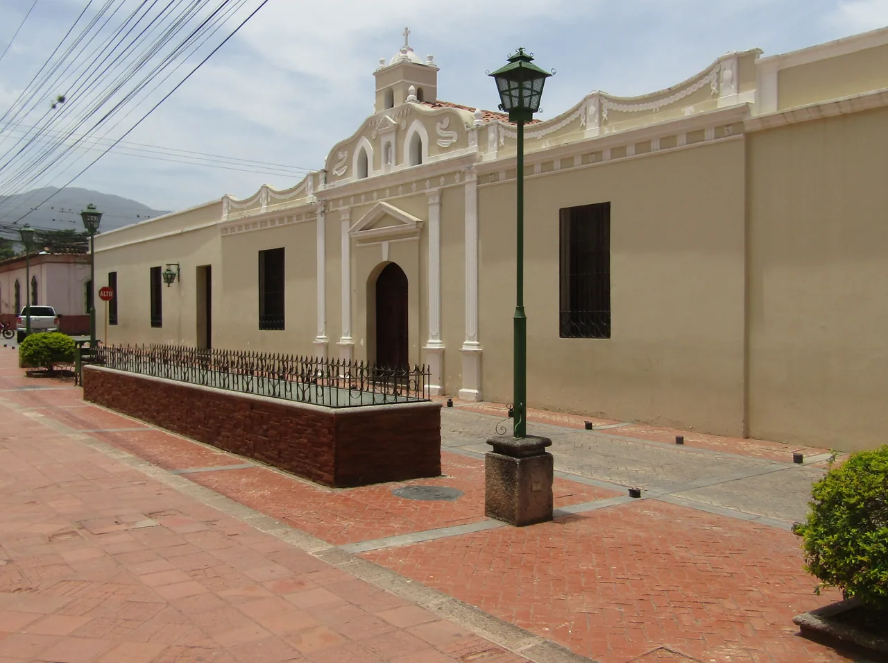 Palacio de fachada clara junto a una calle enlosada y una farola verde.