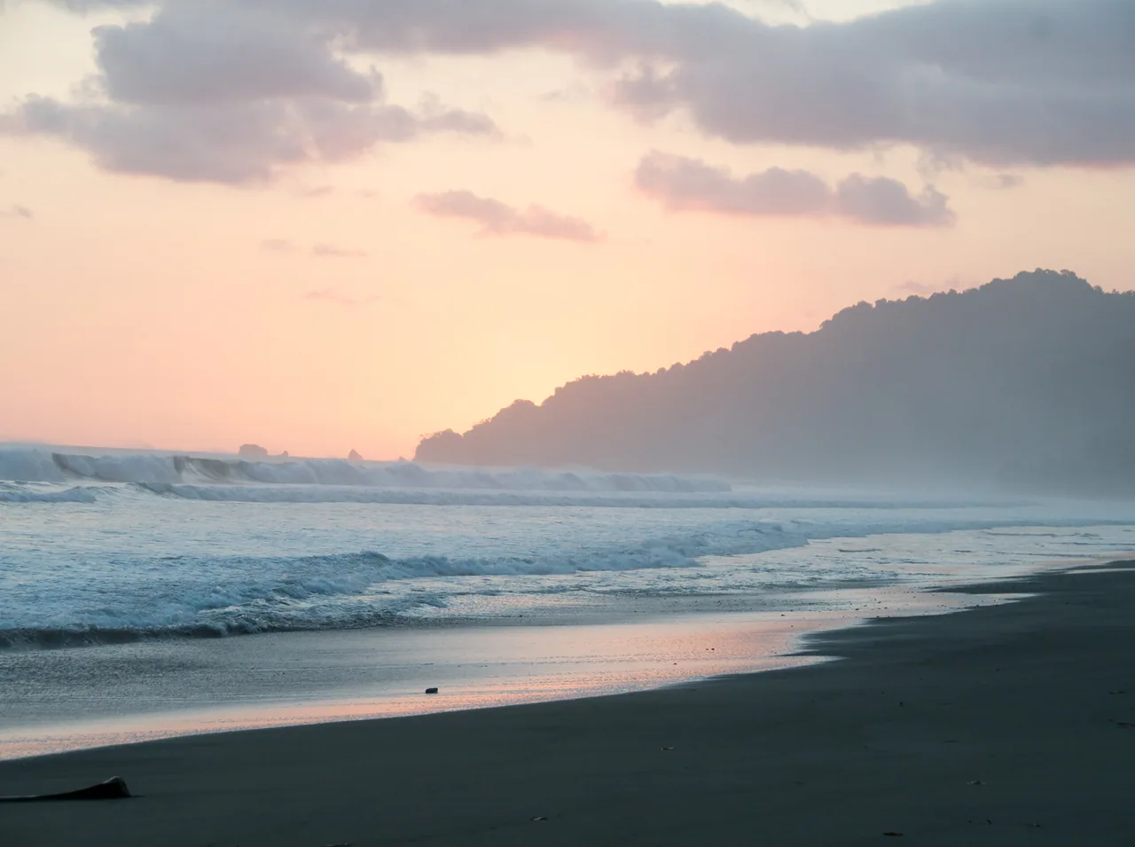 Waves and the forested La Leona coastline at sunset.