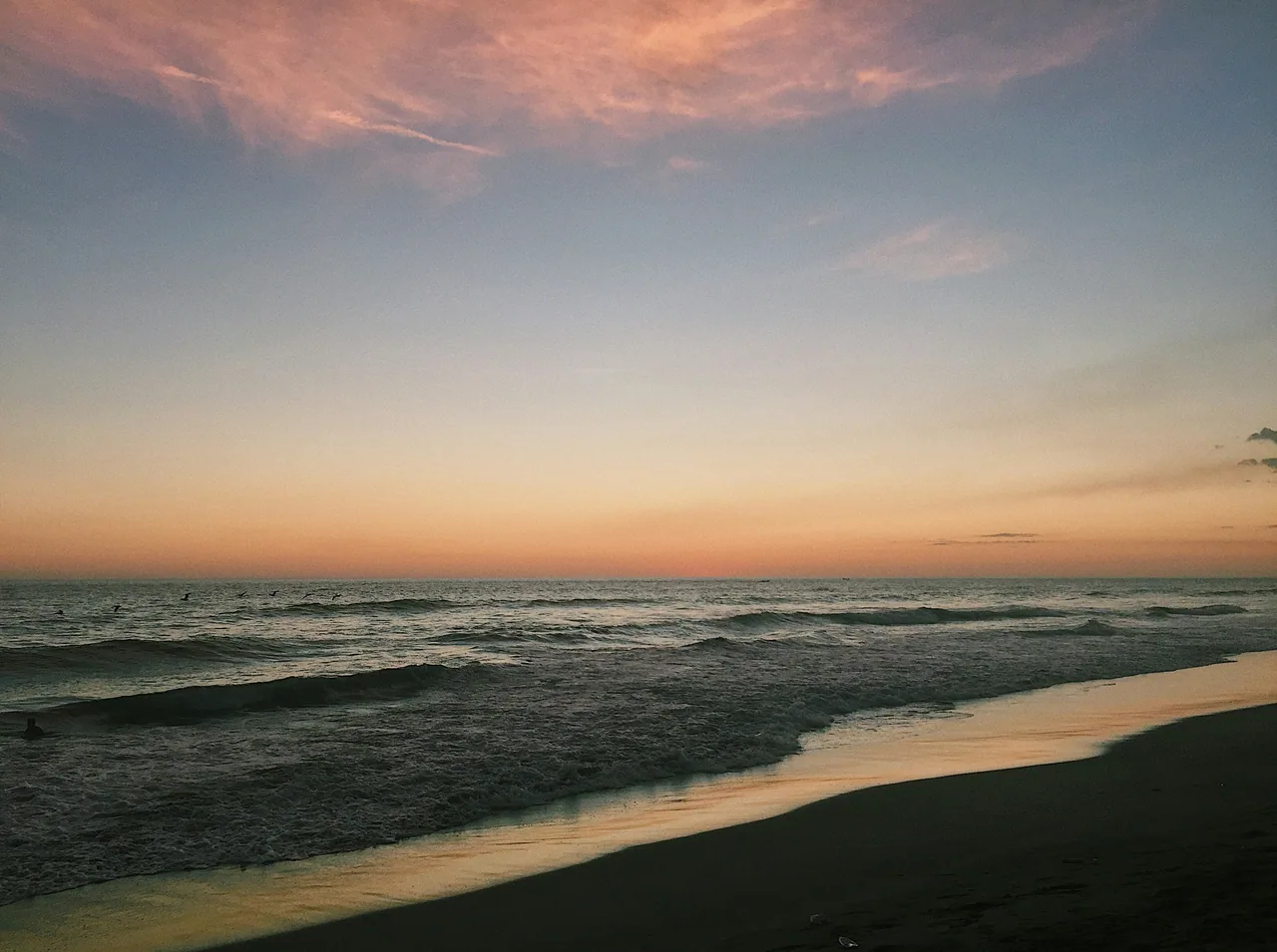Olas y arena de Costa del Sol bajo el cielo del atardecer.