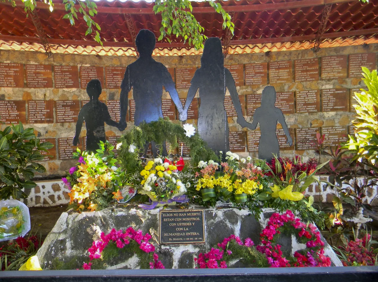 Monumento con siluetas y flores en memoria de las víctimas de El Mozote.