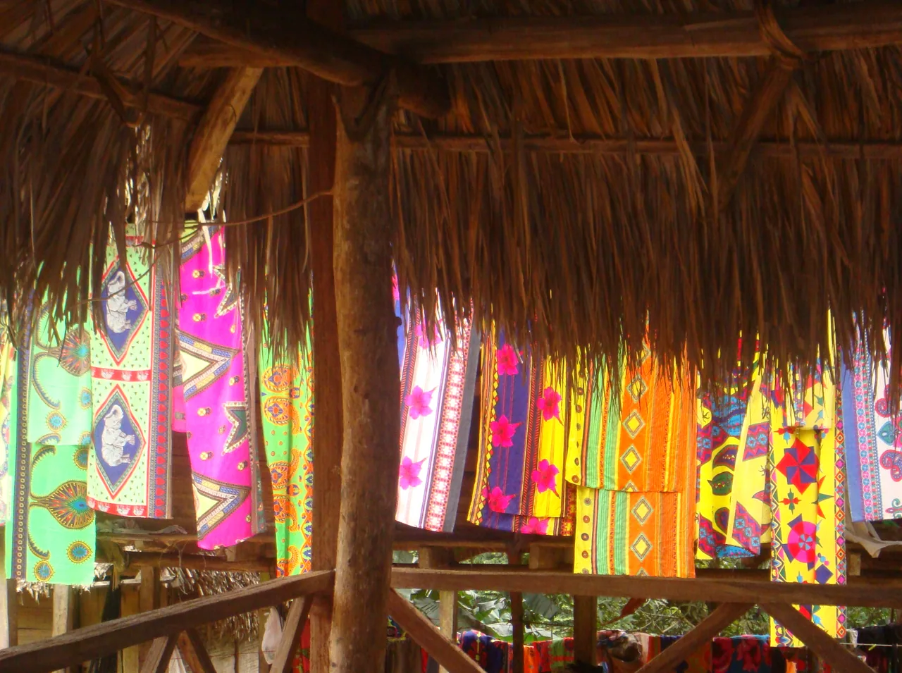 Colorful fabrics hanging beneath a palm-thatched roof in Emberá Drúa.