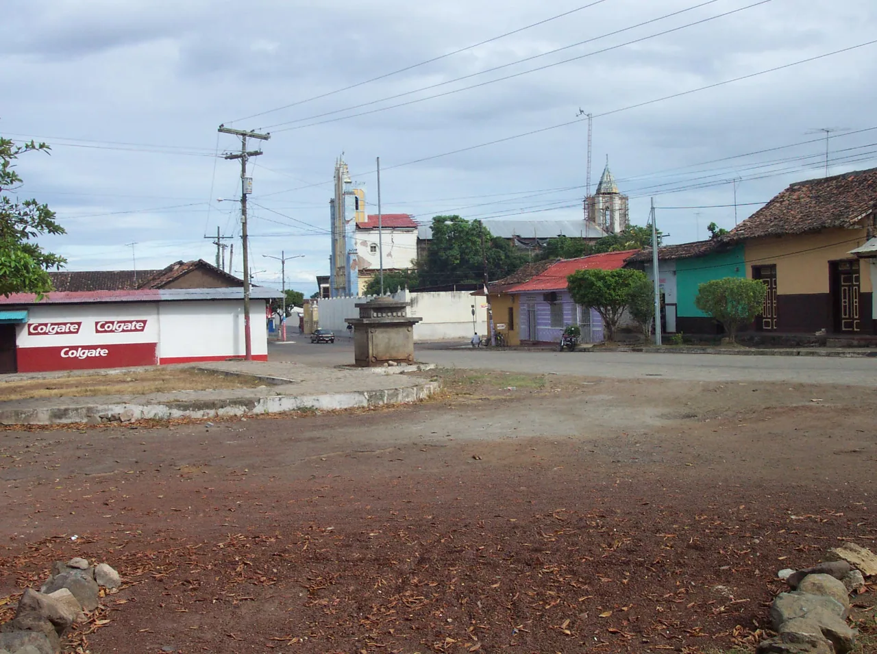 Earthen esplanade with low buildings and a tower in the background.