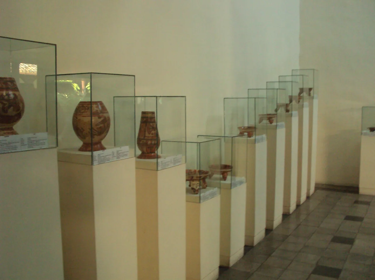 Pre-Columbian pottery displayed in glass cases on white plinths.