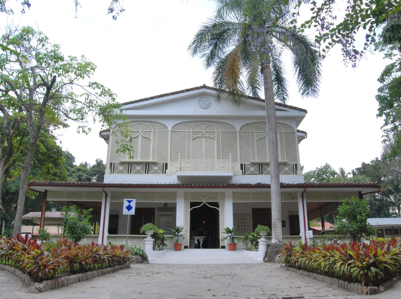 Edificio blanco del Museo de Historia Natural de El Salvador entre jardines.