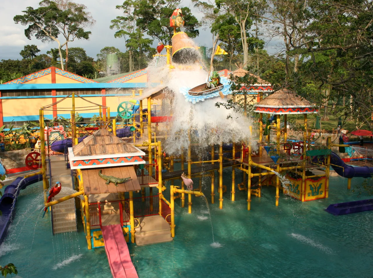 Estructura de juegos acuáticos con toboganes y pasarelas amarillas sobre una piscina.
