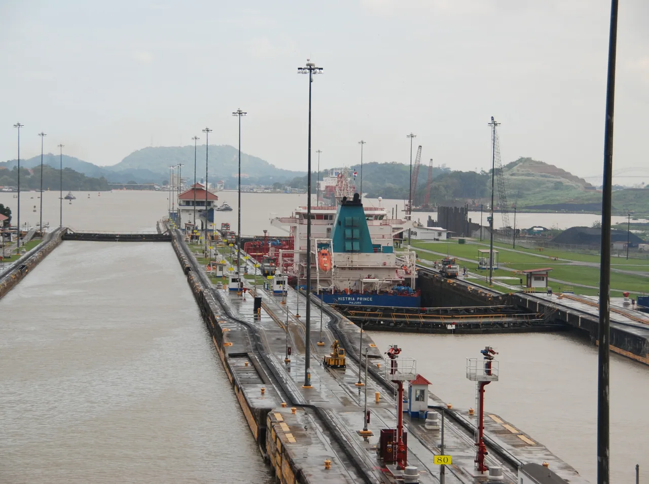 A cargo ship inside Pedro Miguel Locks, with the two canal chambers and hills in the background.