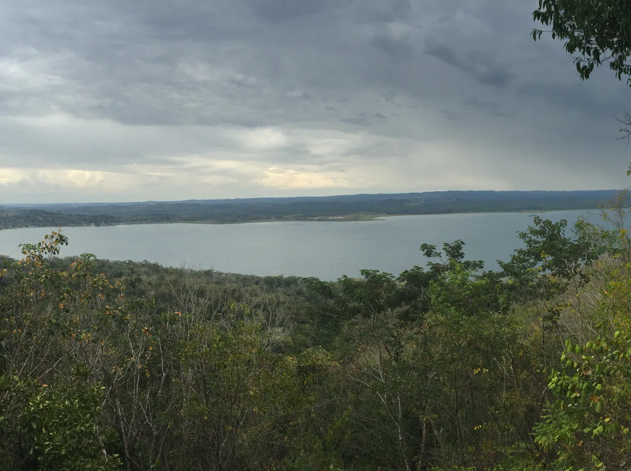 Lago Petén Itzá y bosque vistos desde un mirador del Cerro Cahuí bajo cielo nublado.