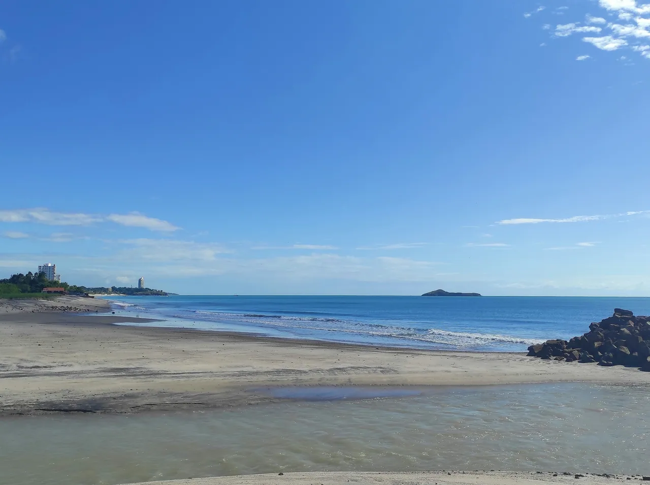 Sandy shore, rocks and a distant islet at Playa Blanca.