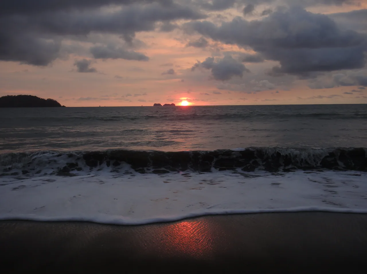 Sunset over the sea and foamy waves at Playa Potrero.