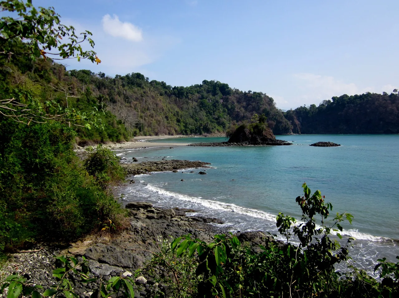 Puerto Escondido bay with a rocky shore, an islet and forest in Manuel Antonio.