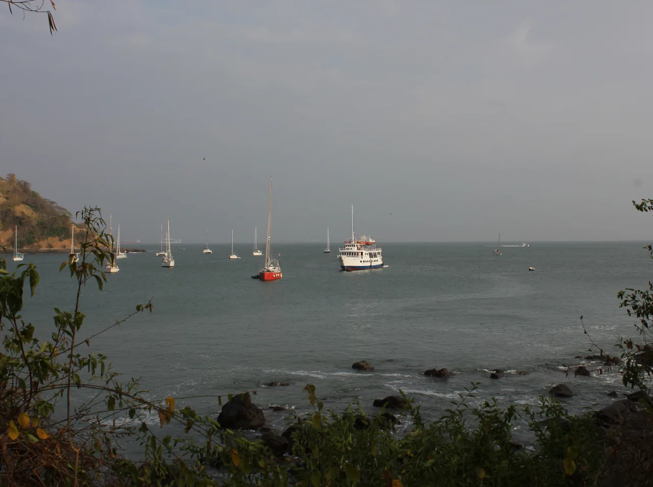 Veleros y un barco fondeados frente a la costa rocosa de Punta Culebra.