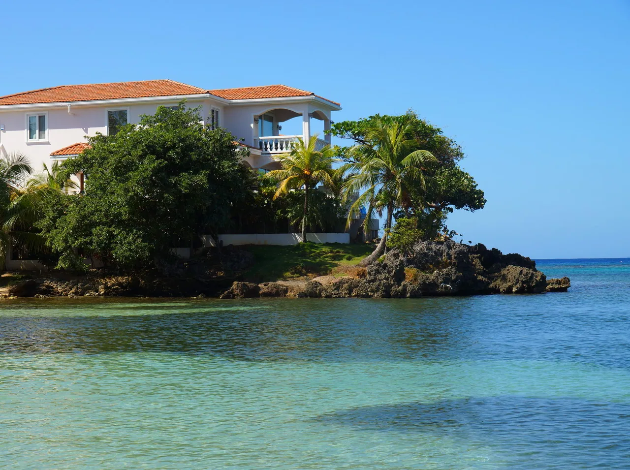 Casa blanca y palmeras sobre una punta rocosa de Half Moon Bay.
