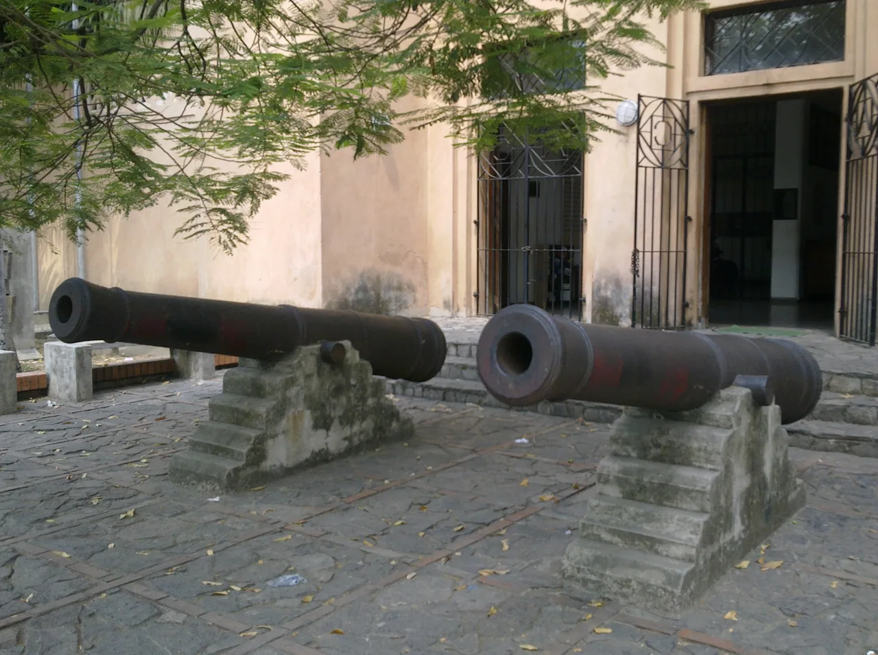 Two old cannons on stone bases in front of a building in San Pedro Sula.